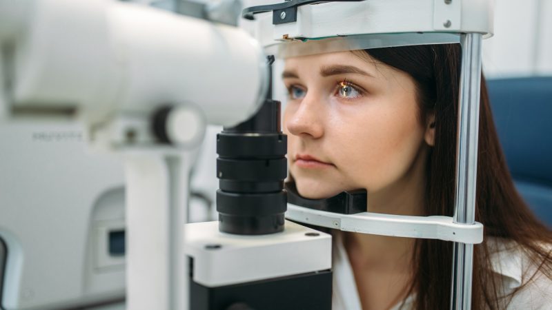 Female patient on eyesight test, optician cabinet